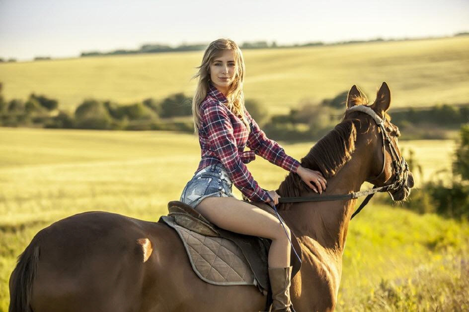 Frau reitet auf einem Pferd über grüne Felder